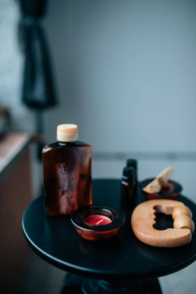 Collection of aromatherapy bottles, candles, and massage tools on a dark table.